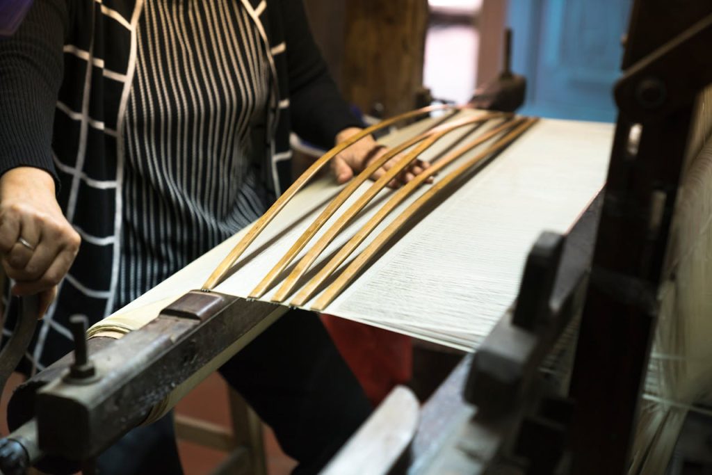 A close-up view of a worker operating a loom machine in a weaving factory, showcasing traditional craftsmanship.