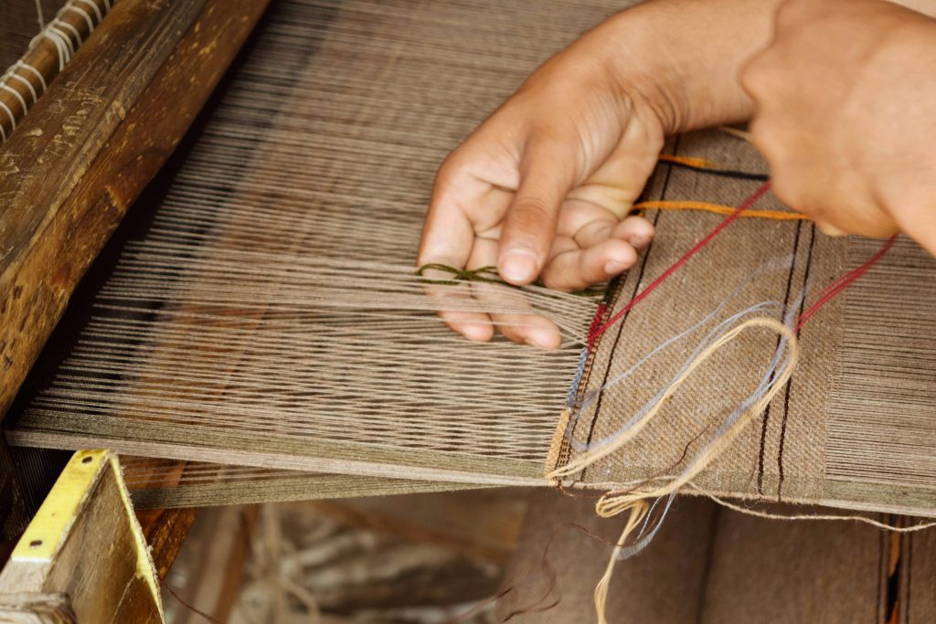 Close-up of hands weaving a khaddi chadar on a loom in Islampur, Pakistan.