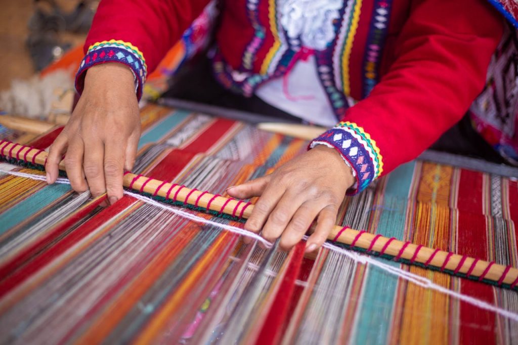 Close-up of a woman weaving colorful textiles by hand in Cusco, Peru, showcasing traditional craftsmanship.