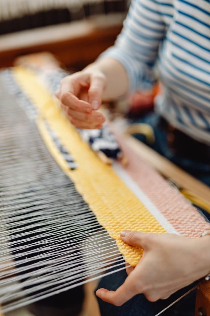 Close-up view of hands weaving a colorful textile on a loom, showcasing intricate craftsmanship.