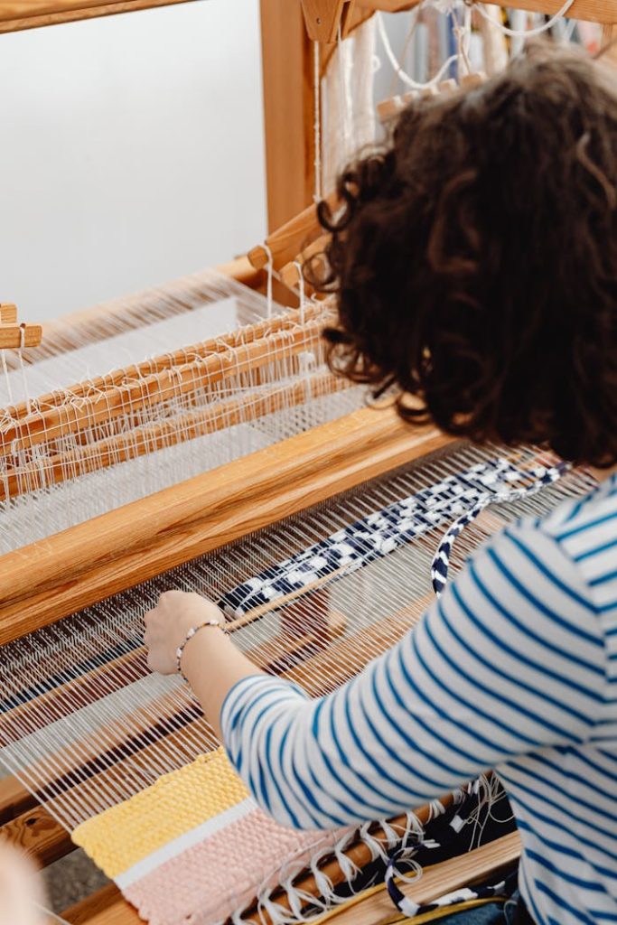 A person skillfully weaving on a wooden loom, focusing on intricate textile craftsmanship.