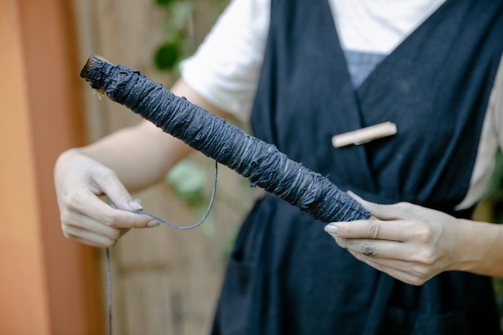 Close-up of hands holding indigo dyed thread, showcasing artisanal craftsmanship in natural lighting.