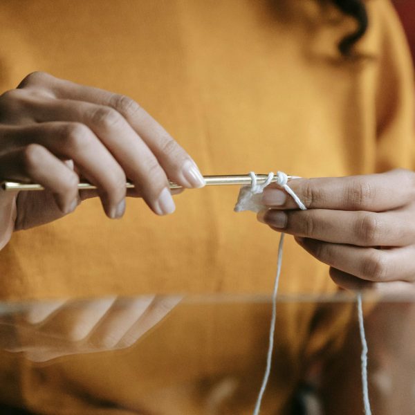 Detailed image of hands crocheting with a crochet hook and yarn, highlighting the crafting process.