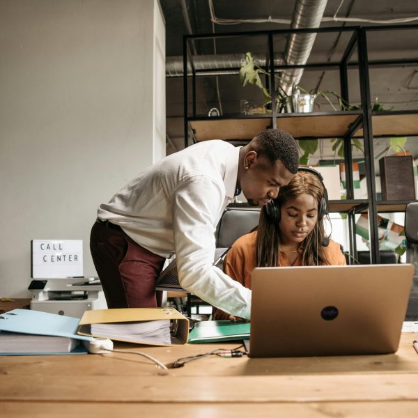Two call center employees collaborating and working with a laptop.